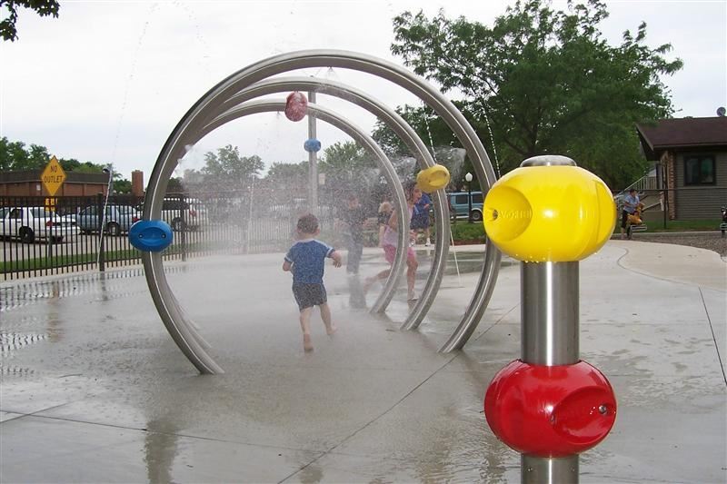 A little boy walking through a water sprinkler.
